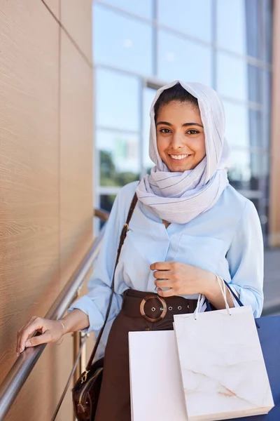中东美女拿着购物袋 对着相机微笑 带着购物袋离开商场的垂直画像 — 图库照片