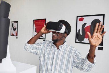 Modern sanat galerisi sergisinde büyüleyici deneyimin tadını çıkarırken gülümseyen Afro-Amerikan erkek portresi.