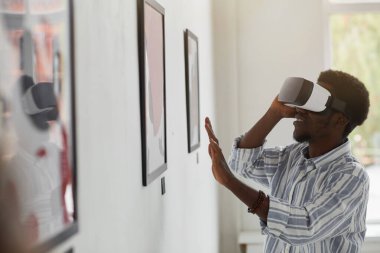Modern sanat galerisi sergisi, fotokopi alanı gibi ilginç tecrübelerin tadını çıkarırken gülümseyen Afro-Amerikan bir adamın yan görüntüsü.