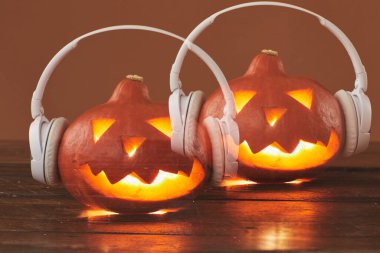 Yatay yakın çekim, Jack O 'Lantern' in kahverengi arka planda beyaz kulaklık taktığı birçok sergi fotoğrafı.