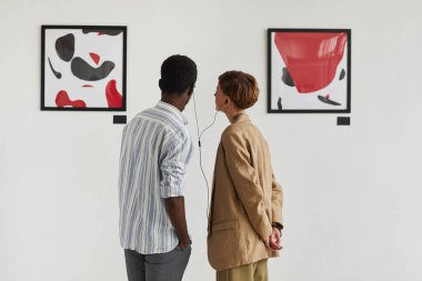Resimlere bakan ve ses rehberini paylaşan iki gencin grafiksel arka plan portresi, modern sanat galerisi sergisi, kopyalama alanı
