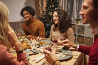 Orta Doğulu yetişkin kadın portresi. Arkadaşları ve ailesiyle evde yemek yerken mutlu bir şekilde gülümsüyor.