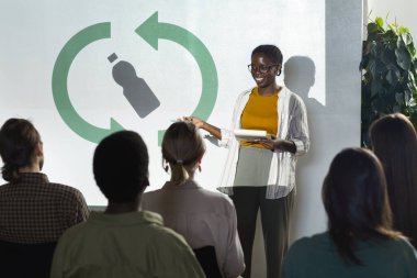 Çevre konferansı sırasında geri dönüşüm ve atık yönetimi üzerine konuşma yapan genç Afro-Amerikalı kadın portresi, kopyalama alanı