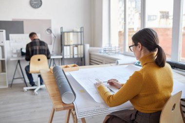 Kadın mimarın arka plan portresi ofiste otururken planlar çiziyor, boşluğu kopyalıyor