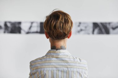 Graphic back view portrait of tattooed young woman looking at paintings at contemporary art exhibition, copy space clipart