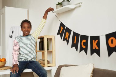 Neşeli Afrikalı Amerikalı çocuk Cadılar Bayramı partisi için günlük kıyafetler giyiyor.