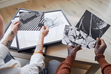 İç dekorasyon için sanat eserlerini seçerken siyah beyaz resimleri tartışan iki modern gencin yüksek açılı görüntüsü, boşluğu kopyala