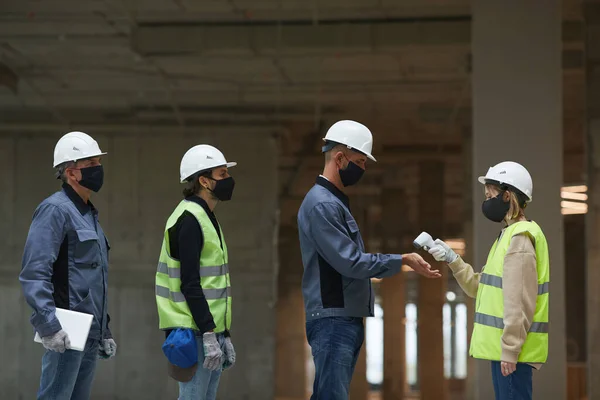 Zijaanzicht Van Vrouwelijke Supervisor Meettemperatuur Van Werknemers Met Contactloze Thermometer — Stockfoto