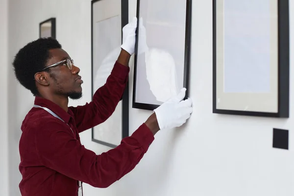 アートギャラリーや展覧会を計画しながら壁にフレームをぶら下げアフリカ系アメリカ人男性でサイドビュー スペースをコピー — ストック写真