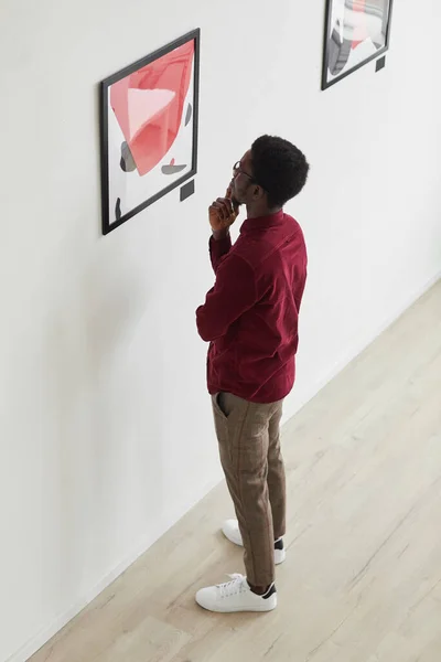 絵画を見て 美術館や美術館の展覧会で考えている若いアフリカ系アメリカ人の男の垂直高角度の肖像画 コピースペース — ストック写真
