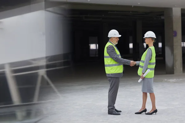 建設現場での投資取引後の女性パートナーと握手する笑顔のビジネスマンの横顔の肖像画 コピースペース — ストック写真