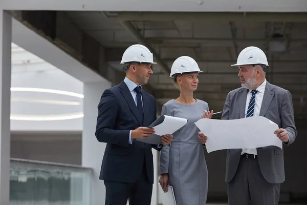 在巡视建筑工地的同时 举着三个头戴硬礼帽 持之以恒的成功商人的肖像 抄袭空间 — 图库照片