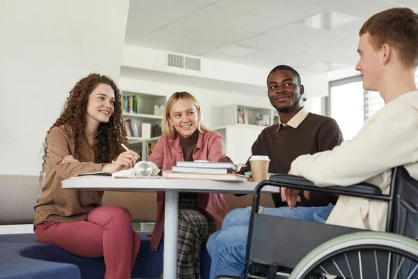大学図書館で学ぶ多民族グループの低角度ビューでは 前景に車椅子を使用して若い男をフィーチャー — ストック写真