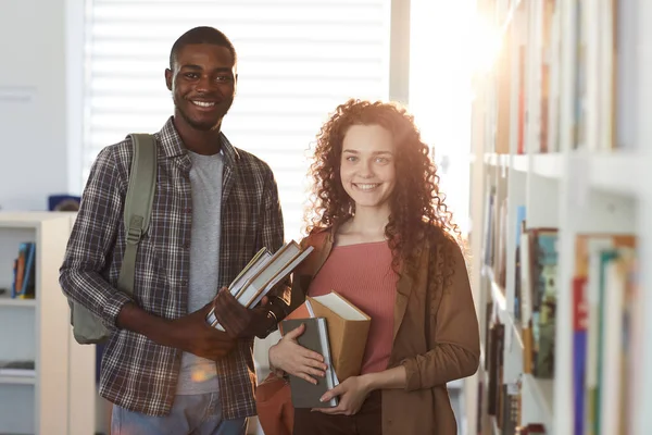 若い女性と大学図書館に立っているアフリカ系アメリカ人の男の腰の上の肖像 両方の本を保持し カメラで笑顔 — ストック写真