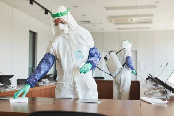 两名卫生工作者穿着防护服在办公室清洁和消毒会议室的肖像 复制空间 — 图库照片