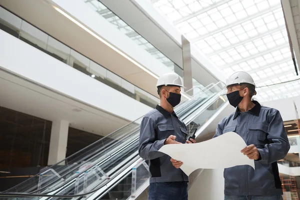 Laaghoekig Portret Van Twee Bouwvakkers Die Maskers Dragen Plannen Bespreken — Stockfoto