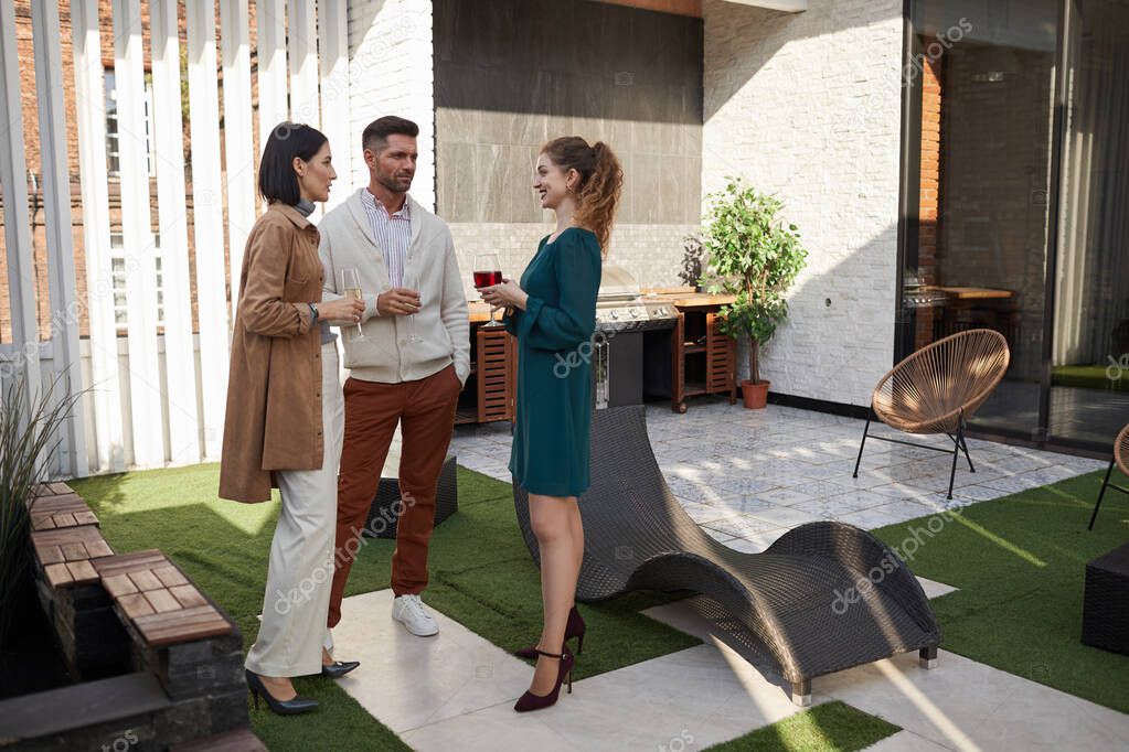 Full length portrait of contemporary adult people chatting while standing at outdoor terrace during party, copy space