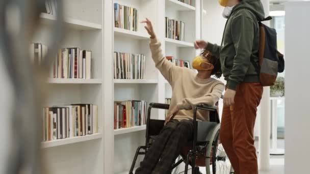 Pełne Ujęcie Niepełnosprawnego Afrykanina Wózku Inwalidzkim Azjatyckiego Studenta Zabierającego Książkę — Wideo stockowe