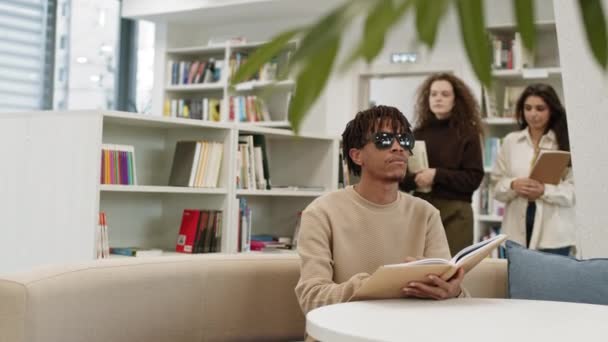 Jovem Cego Africano Usando Óculos Sol Sentado Mesa Biblioteca Lendo — Vídeo de Stock