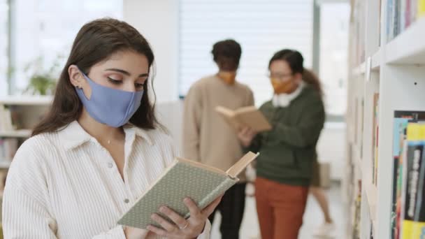 Close Jovem Estudante Raça Mista Usando Máscara Personalizada Livro Leitura — Vídeo de Stock