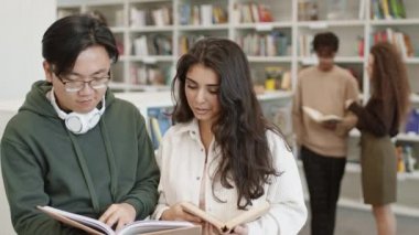 Orta boy, elinde kitap tutan Asyalı bir adam. Karışık ırktan bir kızın yanında duruyor. O da kitabı okuyor, sonra öğrenciler kameraya bakıp gülümsüyor. Halk kütüphanesinde öğrenen insanlar
