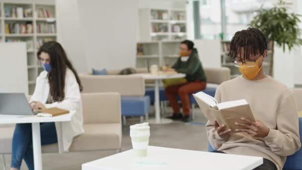 Africano Cara Óculos Máscara Sentado Mesa Biblioteca Pública Livro Leitura — Vídeo de Stock