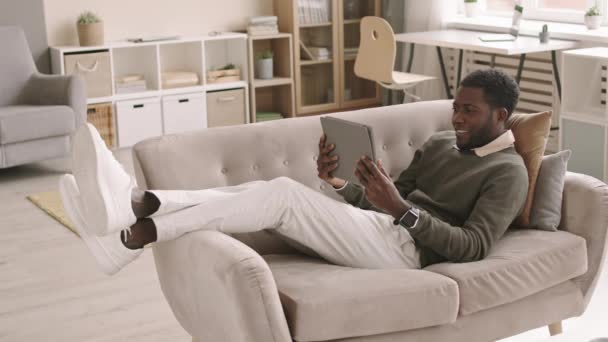 거실에 평상복을 타블렛을 동료와 비디오 채팅을 아프리카계 미국인 사업가의 — 비디오