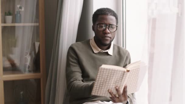 Mediana Toma Joven Africano Con Ropa Casual Gafas Sentado Alféizar — Vídeo de stock