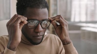 Genç Afro-Amerikalı resepsiyonist, gözlük takıyor ve kulaklık takıyor. Müşteriye telefonla danışmaya başlıyor.
