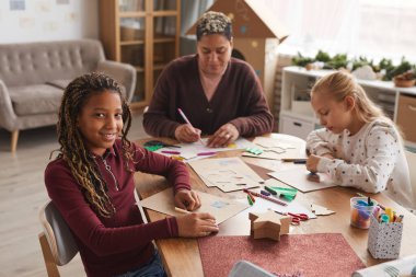 Okulda sanat ve zanaat derslerinin keyfini çıkarırken kameraya gülümseyen Afro-Amerikalı bir kızın portresi.