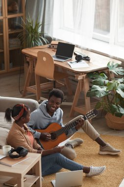 İki genç Afro-Amerikalı müzisyenin birlikte gitar çalıp müzik yazarken dikey açılı portresi.