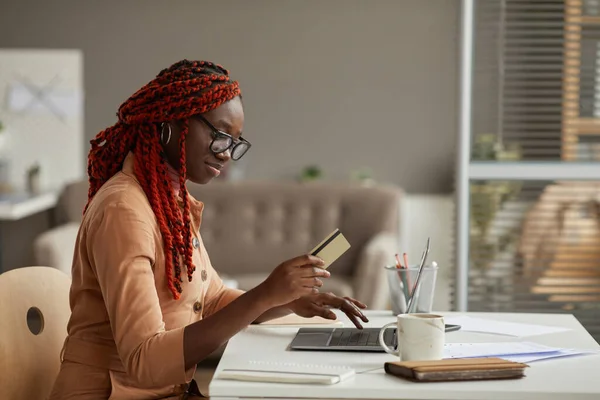 自宅でオンラインショッピングを楽しみながらクレジットカードを保持している若いアフリカ系アメリカ人女性のサイドビューの肖像画 コピースペース — ストック写真