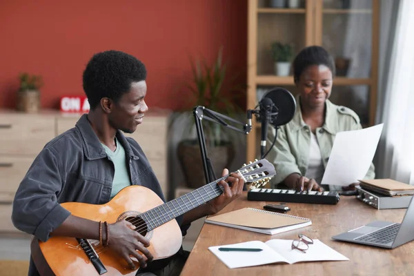 非洲裔美国年轻人在家庭录音室里一边弹吉他一边谱曲的侧景肖像画 复制空间 — 图库照片