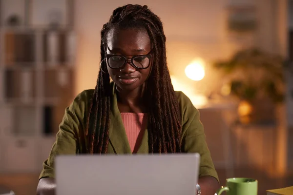オフィスや家庭で働いている間 ラップトップを使用している若いアフリカ系アメリカ人女性のフロントビューの肖像画は 居心地の良い薄暗い照明によって照らされ スペースをコピー — ストック写真