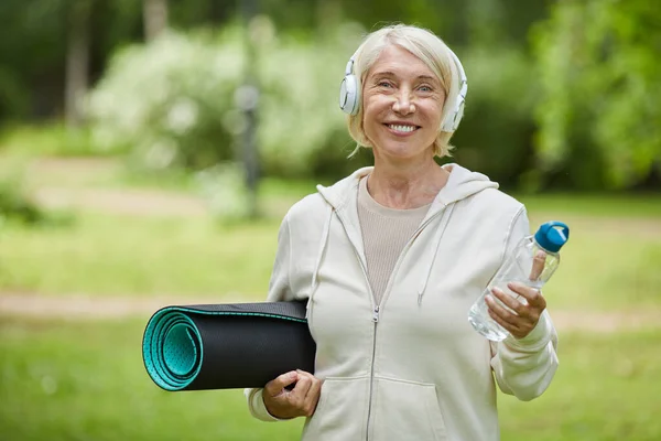 Mellomstort Portrettbilde Glad Kvinne Med Hvite Hodetelefoner Med Yogamatte Flaske – stockfoto