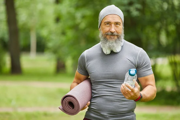 Potret Pria Senior Berjanggut Tampan Memegang Tikar Yoga Dan Botol — Stok Foto