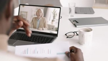 Bilgisayarın önünde oturan ve internet bağlantısı ile orta yaşlı beyaz bir kadınla dokümanları tartışan tanınmayan Afro-Amerikan genç adamın arka görünüşü