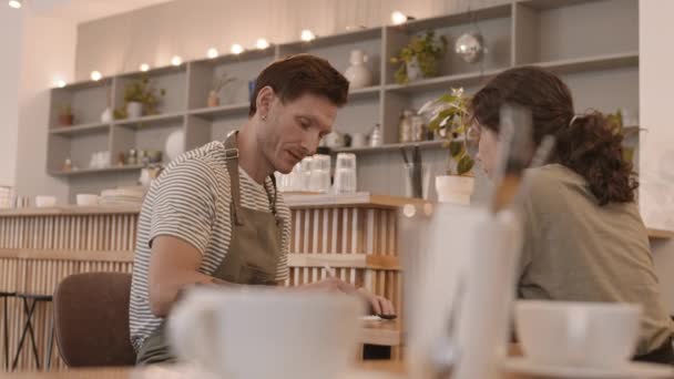 Ujęcie Łukowe Białowłosego Pracownika Cateringu Siedzącego Przy Stole Kawiarni Piszącego — Wideo stockowe