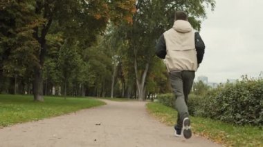 Parkta koşan spor giysiler ve spor ayakkabılar giyen orta yaşlı beyaz bir adam.