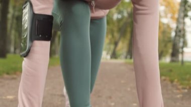 Spor kıyafetleri ve spor ayakkabıları giymiş, parkta koşmaya hazırlanan beyaz bir kadın.