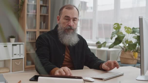Medium Närbild Skäggig Senior Kaukasisk Man Sitter Vid Skrivbordet Hemmakontoret — Stockvideo