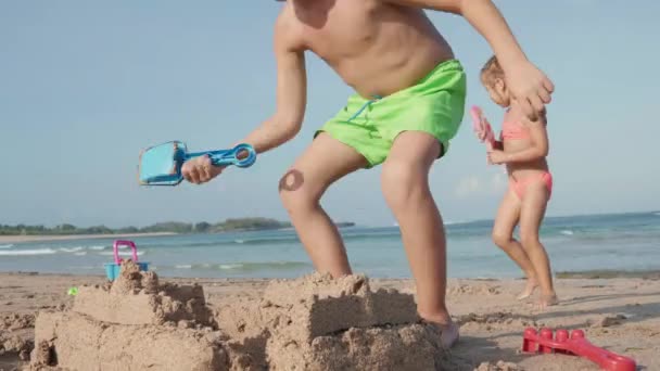 白人男孩和他可爱的妹妹身穿泳衣 在海滩上玩玩具 一起建造沙堡的全景照片 — 图库视频影像