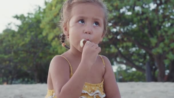 노란색 드레스를 해변에 귀여운 코카서스 소녀의 스틱에 맛있는 아이스크림을 즐기고 — 비디오