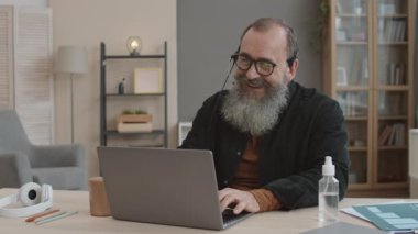 Mikrofonlu kulaklık takan üst düzey beyaz adamın göğüs kafesini kaldır, ofis masasında otur, sinir bozucu bir video görüşmesi yap, sahte gülümseme yap, arkasından nefes ver, el dezenfektanı kullan.