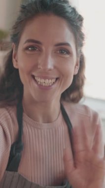 Kahverengi gözlü güzel beyaz kızın dikey el kamerası görüntüsü gülümseyen, konuşan, el sallayan, selfie kamerasıyla çekim yapan.