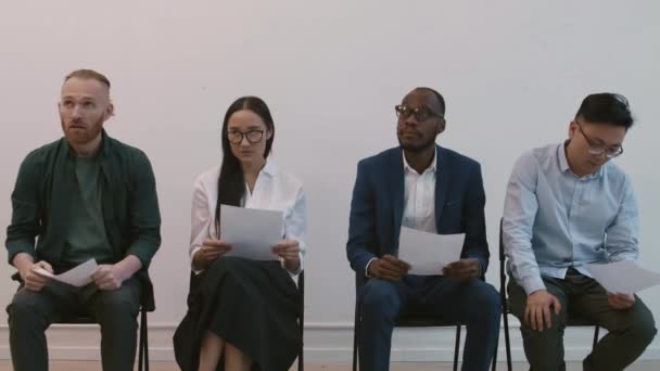 Medium Long Shot Four Multiethnic Impatient People Sitting Chairs Hallway — Stock Video