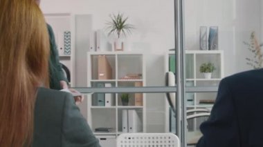 Omzunun üstünden, iş yerinde tanınmayan mülakatçıların önünde masaya oturan, selamlayan, konuşan sakallı, beyaz bir adam.
