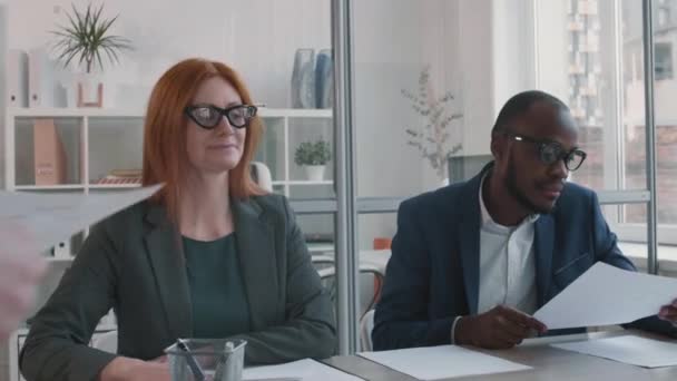 非洲商人与白种人红头发的女性招聘经理坐在一起 进行了中等程度的特写镜头 与无法识别的候选人进行工作面试的公司人员 — 图库视频影像