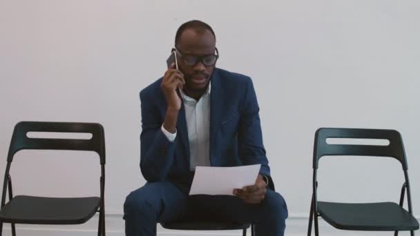 Mittellang Sitzt Ein Junger Afrikanischer Geschäftsmann Auf Einem Stuhl Telefoniert — Stockvideo