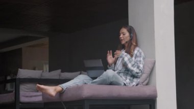 Modern evdeki gündelik giysiler ve kulaklıklar takan, dizlerinin üstüne çöküp, müşteriyle telefonda konuşan genç ve uzun saçlı kadınların kilitlenmesi.